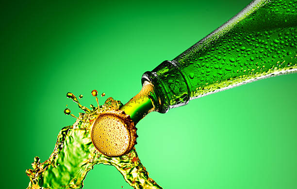 Beer bottle splashing Beer green bottle neck and cap macro shot. Bottle opening with exploding and splashing opening bottle cap photos stock pictures, royalty-free photos & images