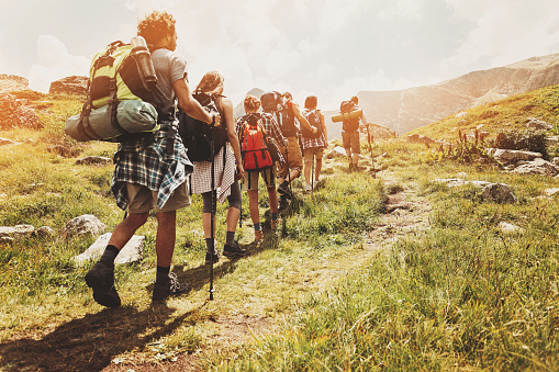 Group of hikers walking in line on a footpath in the mountain, with copy space