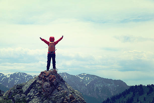istock cheering successful woman backpacker open arms on mountain peak 589545588