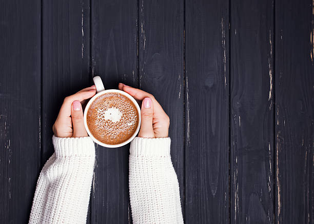 istock Woman's hands in sweater holding cup of coffee 589547998