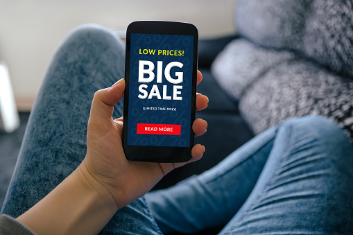 Girl holding smart phone with big sale concept on screen. All screen content is designed by me