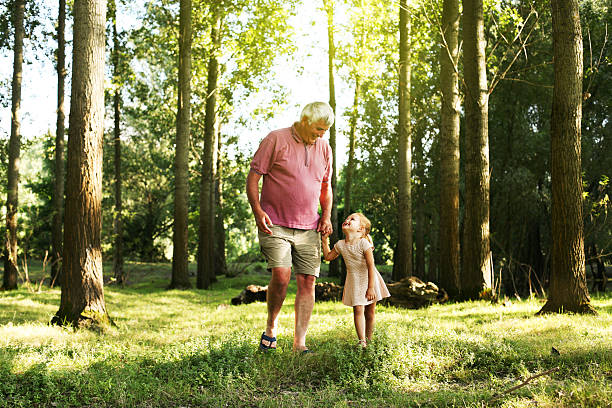 малыш проводит время с дедушкой в парке - grandparent grandfather walking grandchild стоковые фото и изображения