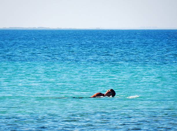 Torre Lapillo, Porto Cesareo, Puglia, Italy - July 19, 2016: a man while swimming early in the morning in the bay of Torre Lapillo.