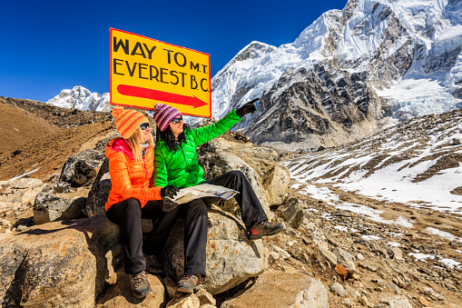 Young women sitting and studying map in Himalayas, Signpost 