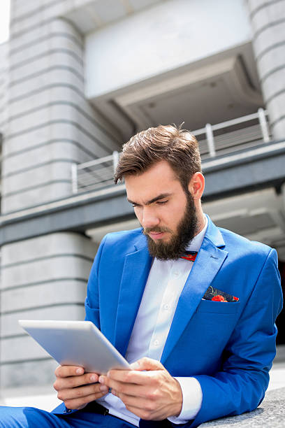 businessman outdoors surfing the net on touchpad. - surfing wireless vertical outdoors lifestyles imagens e fotografias de stock