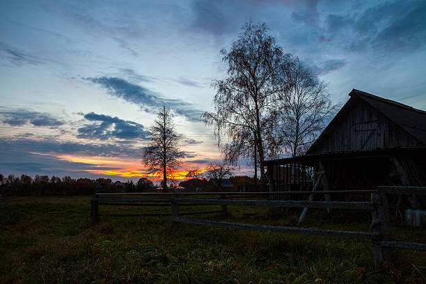 Village view with wooden fence and barn in foreground at beautiful vibrant sunset