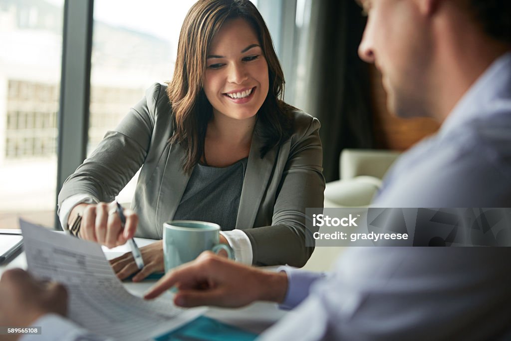 They have a great working relationship Shot of two businesspeople discussing paperwork while sitting in an office Two People Stock Photo
