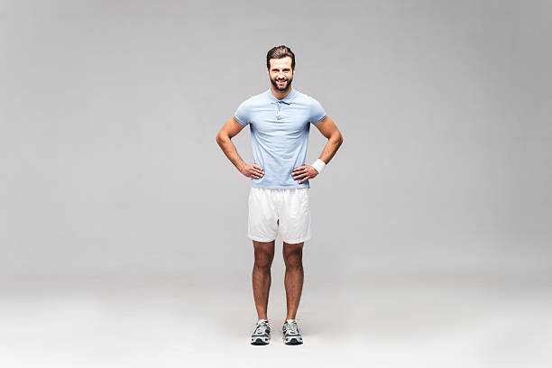 Full length of handsome young man in sports clothing holding hands on hip and looking at camera with smile
