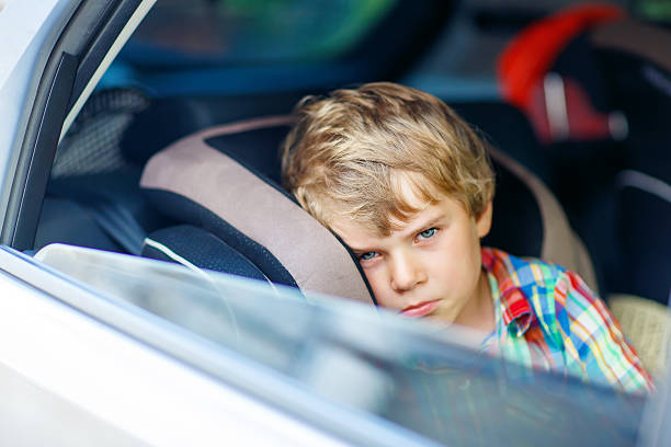 istock Sad tired kid boy sitting in car  during traffic jam 589568964