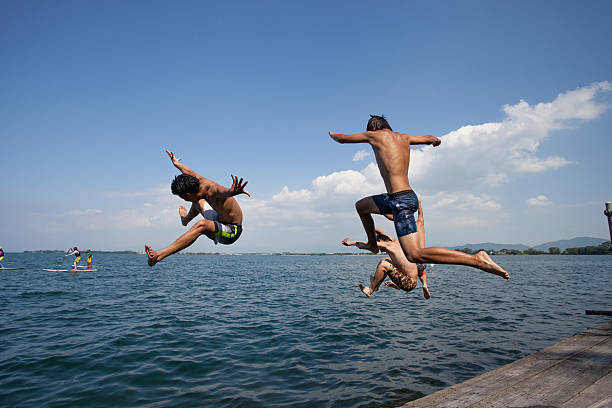 istock Happy young Japanese boys jumping into a lake 589569370