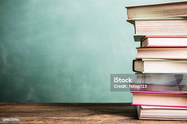 Libros De Texto Apilados En El Escritorio De La Escuela Con Fondo De Pizarra Foto de stock y más banco de imágenes de Libro