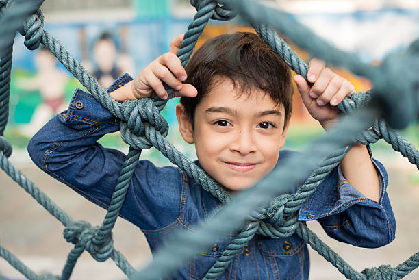 istock Little boy climbing on the rope at playground 589579816