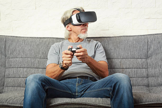 istock Senior man on couch, playing a VR game 589581428