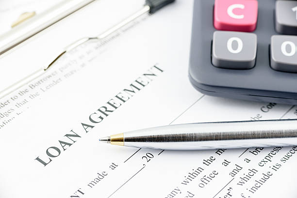 Blue ballpoint pen and a calculator on a loan agreement. Blue ballpoint pen and a calculator on a loan agreement, preparation for filling and signing a form on a clipboard. borrowing stock pictures, royalty-free photos & images