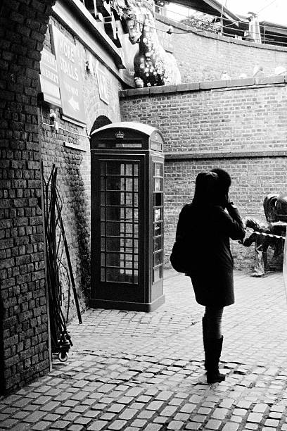 Stables Market London,UK - March 6, 2016: Backlit woman walking out of Stables market in Camden, North London. In the baclground is a red GPO telephone box. british telecom photos stock pictures, royalty-free photos & images