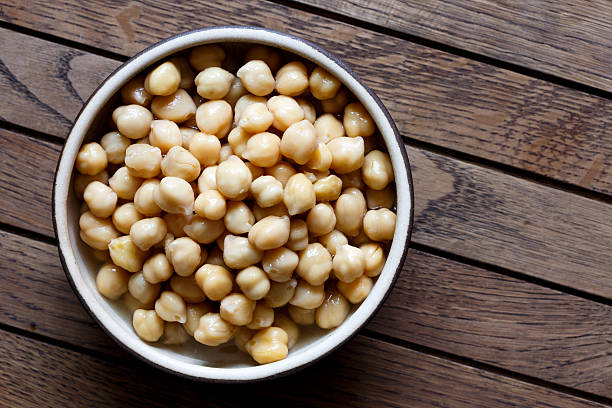 istock Cooked chickpeas in brown ceramic bowl isolated on dark. 589937924