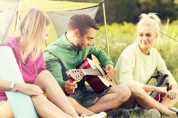 istock Group of friends camping in forest and playing guitar 589939814