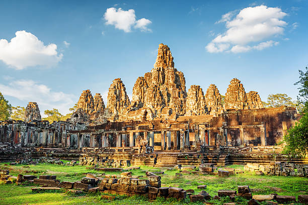 Main view of ancient Bayon temple in Angkor Thom, Cambodia Main view of ancient Bayon temple in Angkor Thom in evening sun. Mysterious Angkor Thom nestled among rainforest in Siem Reap, Cambodia. Enigmatic Angkor Thom is a popular tourist attraction. cambodian culture photos stock pictures, royalty-free photos & images
