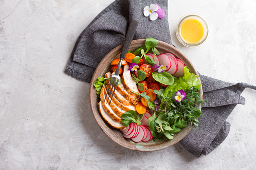 Spring salad with vegetables, chicken breast and edible flower for healthy dinner, selective focus