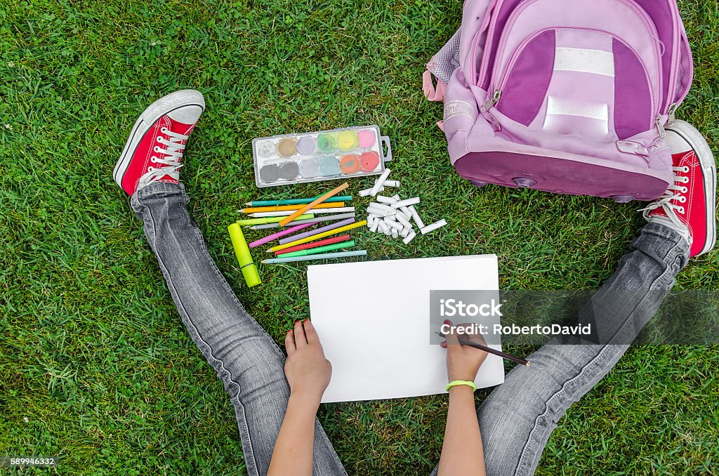 view from up on school supplies view from up on school supplies, a girl sitting on the grass and draws Teenager Stock Photo