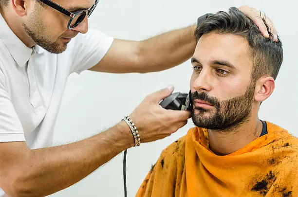 Photo of Barber takes care of customer chin with hair trimmer