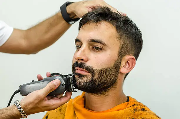 Photo of Barber takes care of customer chin with hair trimmer