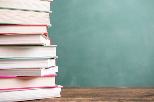 istock Textbooks stacked on school desk with chalkboard background. 589948046
