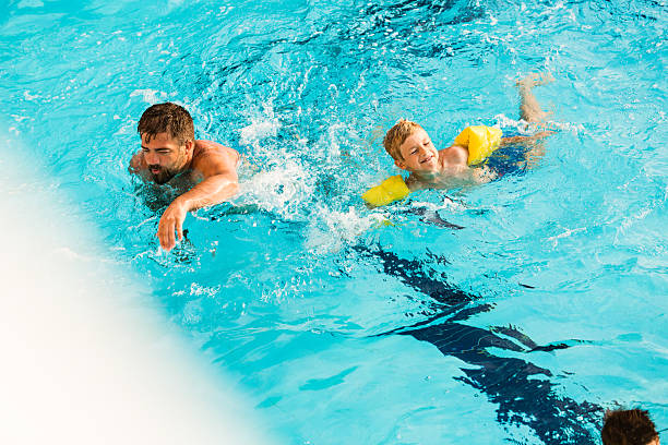 istock Father and son swimming together 589948216