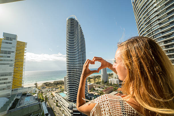 istock Young woman frames Surfers paradise into heart shape finger frame 589949140