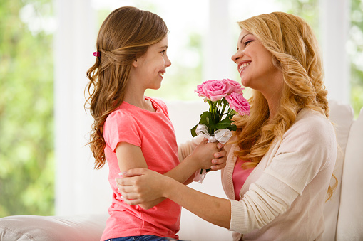 Mother and daughter holding bouquet of flowers