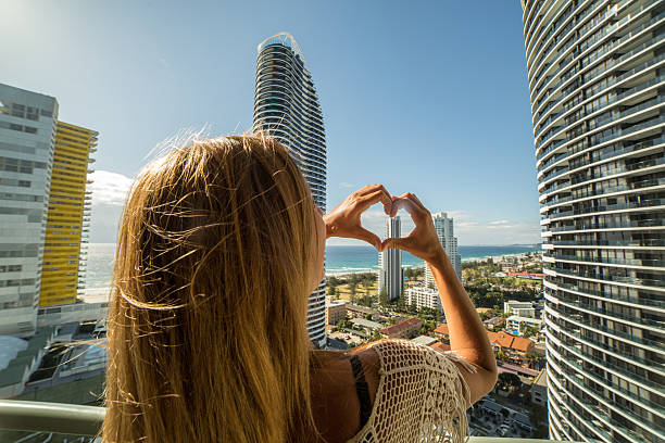 istock Young woman frames Surfers paradise into heart shape finger frame 589949818