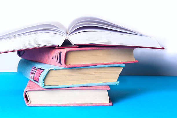 istock Open book, stack of colorful hardback books on light table. 589950212