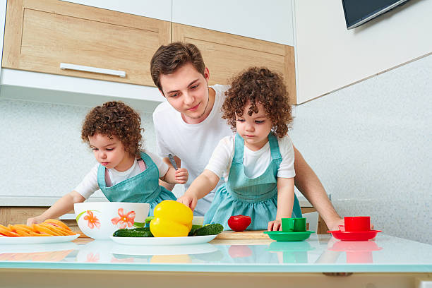 istock Father with daughters twins in the kitchen cooking. Dad teaches 589950932