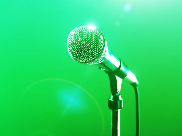 istock Microphone in the spotlight against green background 589953152