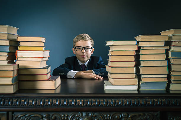 istock Smart school boy sitting at table with many books 589961368