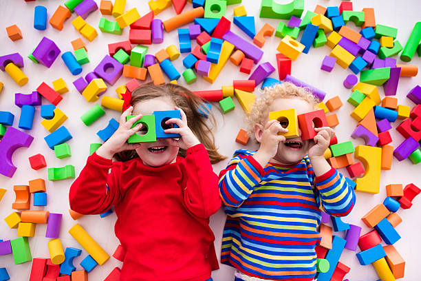 Children playing with colorful blocks building a block tower Happy preschool age children play with colorful plastic toy blocks. Creative kindergarten kids build a block tower. Educational toys for toddler or baby. Top view from above. twin photos stock pictures, royalty-free photos & images