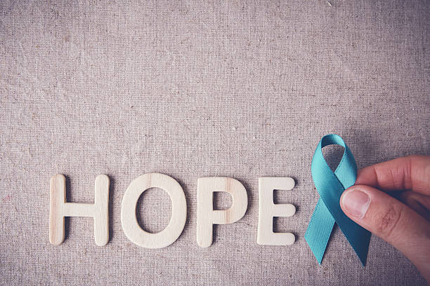 Fingers holding Teal Ribbon with HOPE wooden letters, toning, Ov Fingers holding Teal Ribbon with HOPE wooden letters, toning, Ovarian Cancer, cervical Cancer, Kidney Cancer awareness polycystic ovary syndrome photos stock pictures, royalty-free photos & images