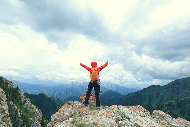 istock cheering successful woman backpacker open arms on mountain peak 589964126