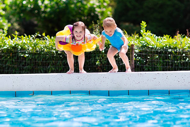istock Little kids jumping into swimming pool 589966228