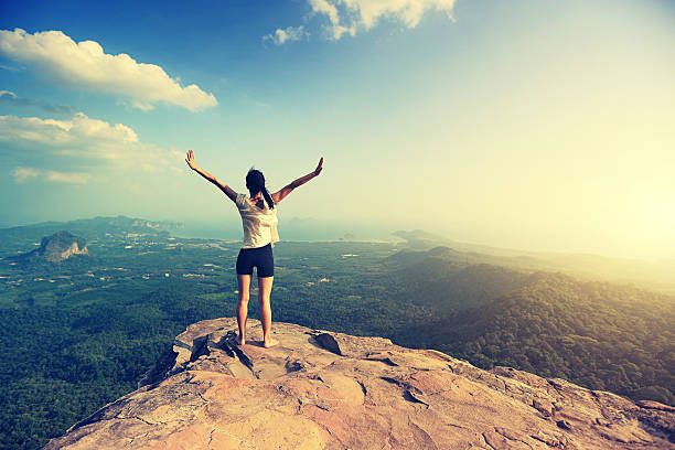 istock young freedom woman open arms on mountain peak 589968620