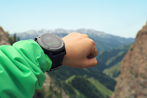 young woman hiker checking the altimeter on sports watch at mountain peak