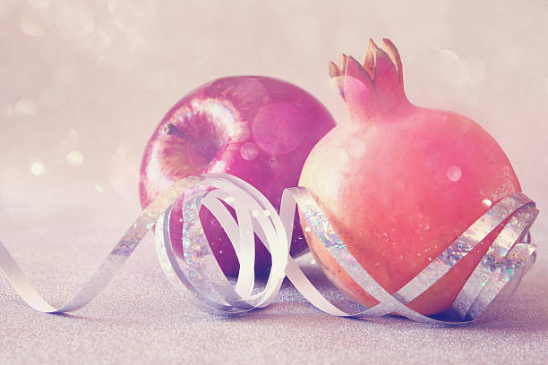 Rosh hashanah (jewish New Year holiday) concept - apple and pomegranate over wooden table. Traditional symbols. Glitter overlay