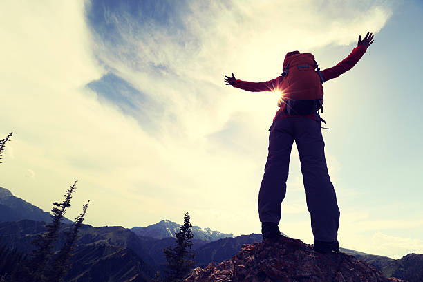 istock cheering successful woman backpacker open arms on mountain peak 589970840