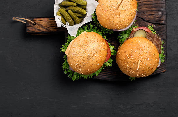 istock Hamburgers, cheeseburger and pickles on wooden massive board 589973810