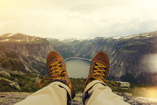 Traveler resting on a mountain plateau. POV view, legs close up on the background of mountain landscape