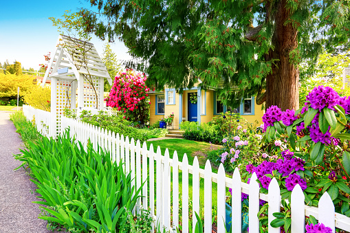 Small Yellow house exterior with White picket fence and Decorative Gate. Northwest,USA
