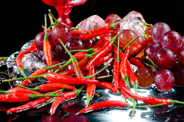 istock Grapes and chilli with wine glass on black background 589983548