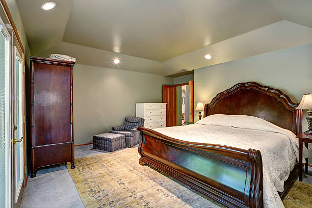 istock Bedroom interior with wooden king size bed and carpet floor. 590033468