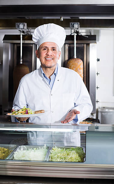 istock Mature man cook holding plate  in cafe 590035844