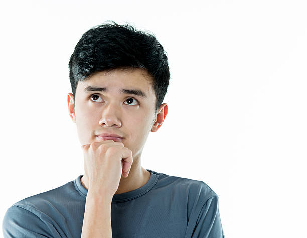 Thoughtful young asian man against white background.